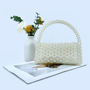 Detailed view of handmade white pearl beaded handbag on magazine with elegant floral decor