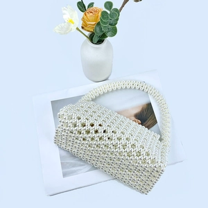 Detail of handmade white pearl beaded bag with long handle placed on a fashion magazine