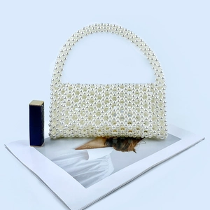 Detail of hand-woven white pearl beads and elegant handle of the handmade shoulder bag