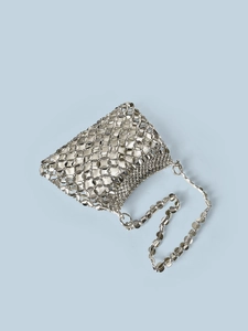 Close-up of silver sequin woven evening bag with round metallic discs on blue background
