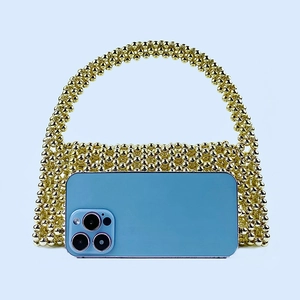 Detailed view of handmade gold beaded handbag with smartphone for scale comparison