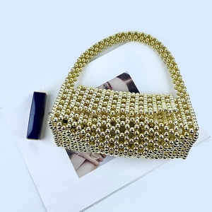 Detailed close-up of handmade gold beaded woven handbag featuring hollow triangle patterns