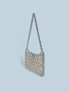 Detail of silver metallic beaded hollow-out bag with cream lining and woven shoulder strap