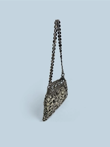Close-up of metallic sequin mesh structure and fine chain strap on retro shoulder bag