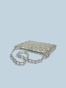 Macro view of silver bamboo-style metallic beads on a woven hollowed-out shoulder bag