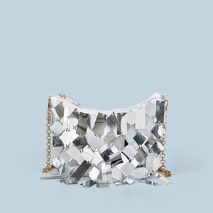 Detailed close-up of sparkling silver sequins and gold chain strap on the evening bag