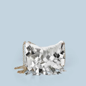 Detailed view of shimmering silver sequins and gold chain strap on festive clutch