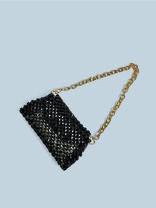 Detail einer schwarzen Perlen-Handtasche mit Pyramidenfacetten und goldener Metallkette