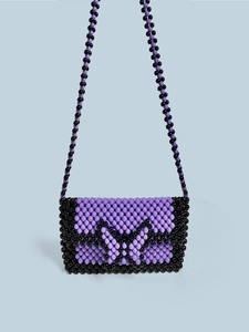 Close-up of handmade purple beaded bag with black butterfly pattern and long strap