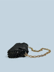 Makroaufnahme der schwarzen 3D-Perlentasche mit markanter goldener Gliederkette