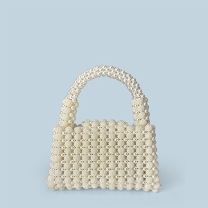 Detail of handcrafted cream pearl woven handbag showing intricate texture and top handle