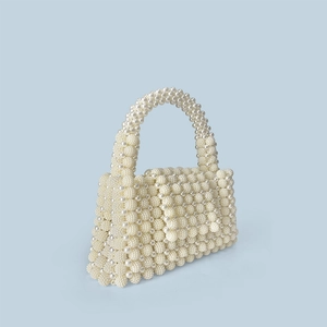 Detail of handmade woven pearl handbag featuring round beads and curved pearl handle