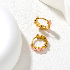 Close-up of pink enamel heart earrings with gold plating on a minimalist white background