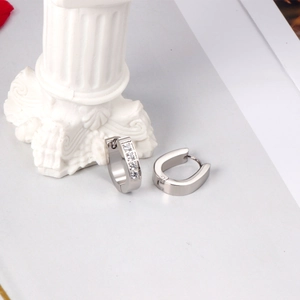 Boucles d'oreilles ovales argentées avec zircons sur fond blanc minimaliste