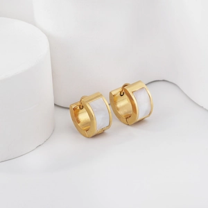 Vue macro de boucles d'oreilles huggie en acier doré avec détails en nacre blanche