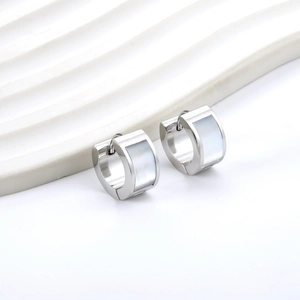 Détail de boucles d'oreilles en acier argenté avec nacre sur un support de présentation