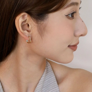 Detail of U-shaped gold heart earring with pavé zircon stones and light blue enamel accent