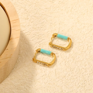 Macro detail of gold-plated rectangular earrings with blue enamel and zircon inlay