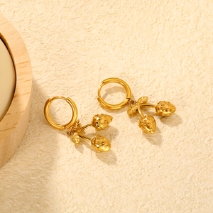 Chic 18K gold strawberry hoop earrings with detailed leaves on a textured warm background