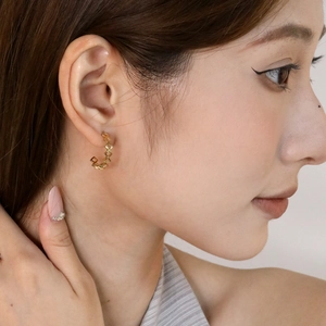 Close-up of golden geometric woven texture C-shaped hoop earrings worn by a model