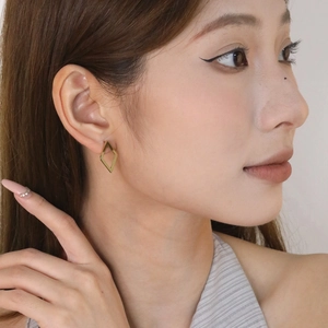 Close-up of a model wearing minimalist 18K gold plated geometric hollow stud earrings