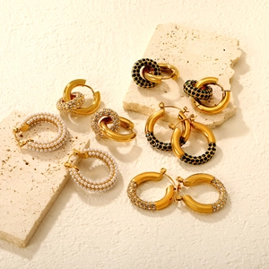 Detail view of gold emerald and pearl earrings on stone display for luxury jewelry style