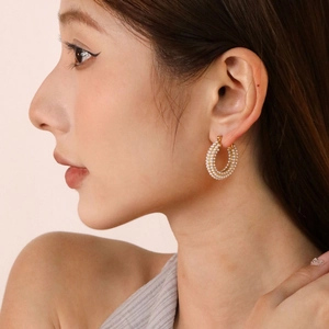 Elegant gold plated stainless steel donut hoop earrings with emerald green accents on model