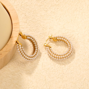 Macro detail of gold-plated hoop earrings with triple rows of pavé white pearls