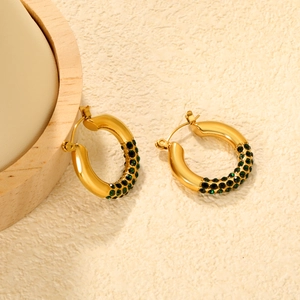 Detailed view of gold plated C-shape hoop earrings with green emerald pavé setting