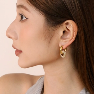 Close-up of model wearing gold double-ring hoop earrings with micro-pave crystals