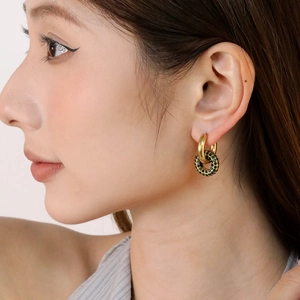 Golden double hoop earrings with emerald green rhinestones worn by a model