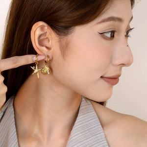 Boucles d'oreilles asymétriques étoile de mer et coquillage avec perles dorées sur modèle