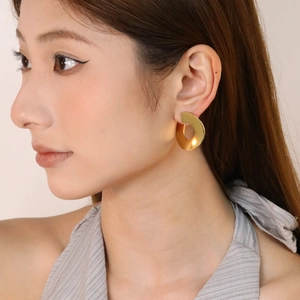 Boucles d'oreilles créoles dorées en forme de C avec finition mate sur modèle