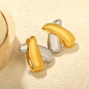 Gros plan détaillé de boucles d'oreilles abstraites bicolores or et argent entrelacées