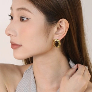 Retro gold oval stud earrings with dark brown tiger eye stone on model in close-up view