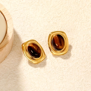 Close-up of vintage gold tiger eye stud earrings with a glossy oval stone finish