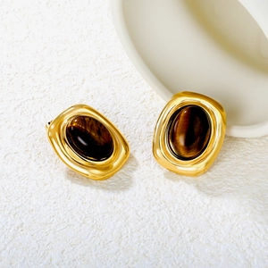 Macro detail of oval tiger eye stone studs with polished gold metallic finish