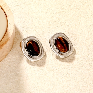 Macro shot of oval tiger eye stones in vintage silver studs on a soft textured surface