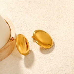 Detailed view of polished oval gold-plated stud earrings on a minimalist white display
