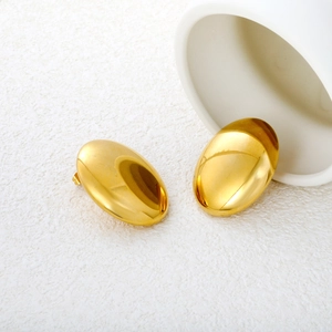 Macro view of polished gold oval stud earrings with high-gloss mirror finish texture