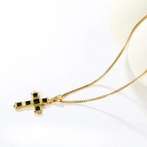 Golden stainless steel cross pendant necklace with green zircons on a white background