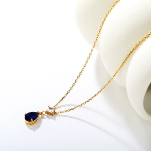 Detail of elegant gold necklace featuring dark blue pear-shaped and square crystal pendants