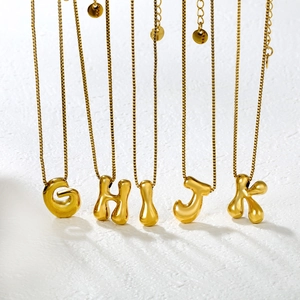Detailed view of golden bubble style initial pendants with sturdy box chain link texture