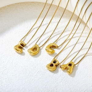 Detail view of five polished gold bubble letter pendants A-E on delicate box chains