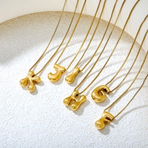 Detailed view of 3D bubble letter necklaces in gold finish with delicate box chains