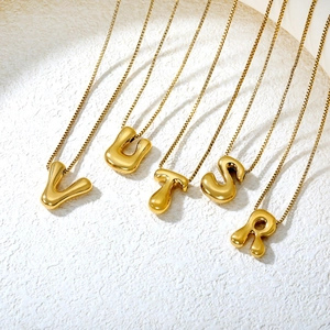 Detailed view of polished golden bubble letter pendants V U T S R on delicate chains