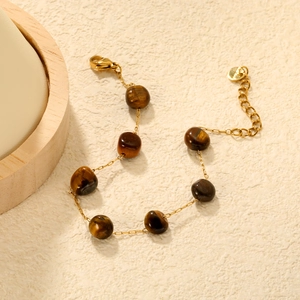 Golden stainless steel bracelet with seven natural tiger eye stones on beige textured surface
