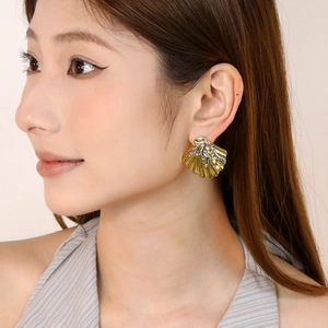 Boucles d'oreilles coquillage bicolores avec perles blanches portées par un mannequin