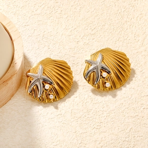 Gros plan sur boucles d'oreilles feston d'or avec étoile de mer et perles blanches