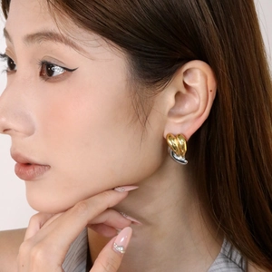 Gros plan de boucles d'oreilles cœur bicolores en acier inoxydable portées par un modèle